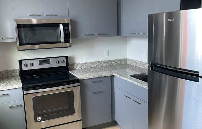 a kitchen with gray cabinets and stainless steel appliances at Colonial Apartments, Orlando, FL 32808