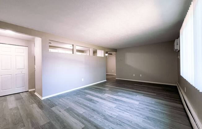 an empty living room with grey and white walls and wood floors