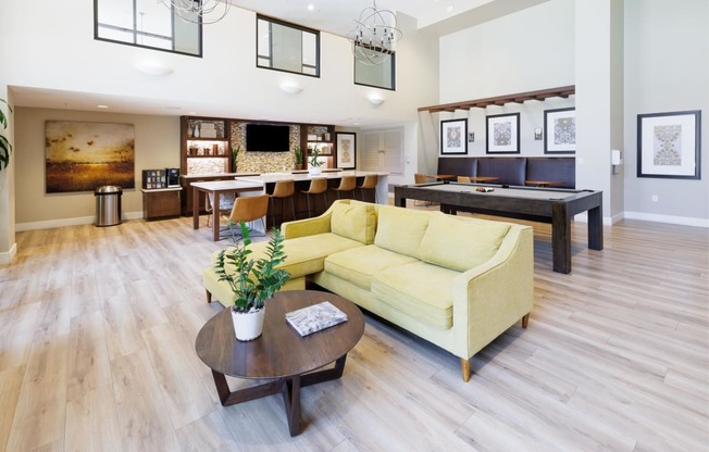 a living room with a yellow couch and a table with a pool