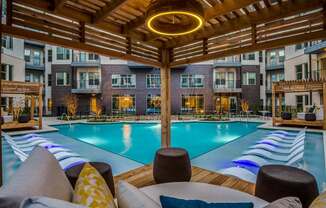 A large outdoor pool area with a wooden pergola and lounge chairs.