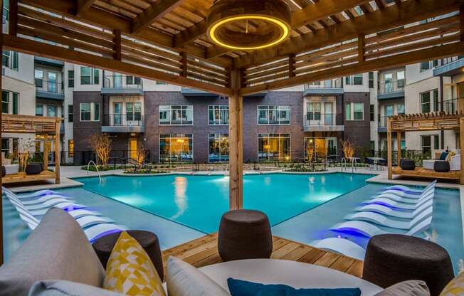 A large outdoor pool area with a wooden pergola and lounge chairs.