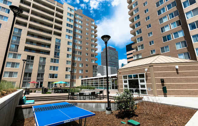 a blue ping pong table is in a courtyard between two tall buildings