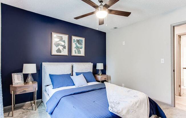 A bedroom with a bed, nightstands, and a ceiling fan.