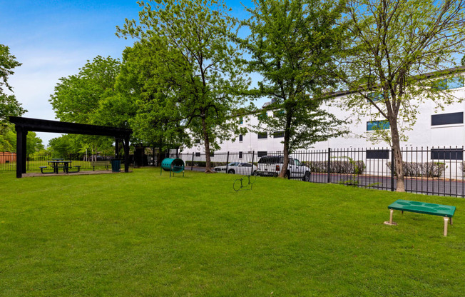 a park with green grass and trees in front of a building