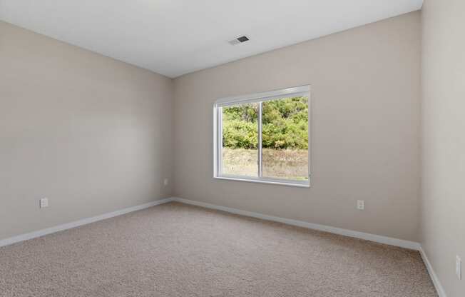 a bedroom with a large window and beige carpet at The Lodge at Overland, Minnesota, 55901