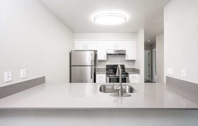 a kitchen with white countertops and a stainless steel refrigerator