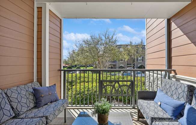 a balcony with two couches and a table and a fence