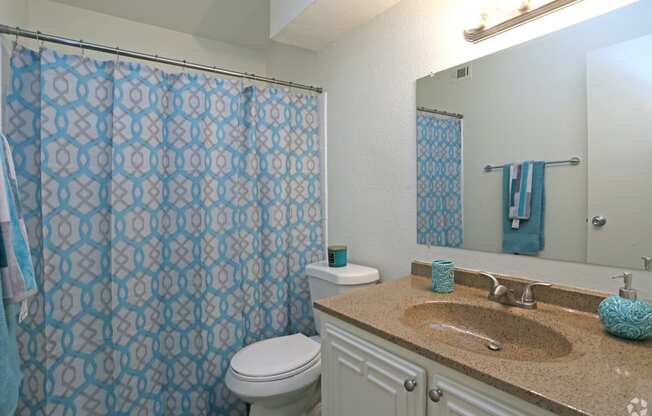 a bathroom with a blue shower curtain and a white toilet