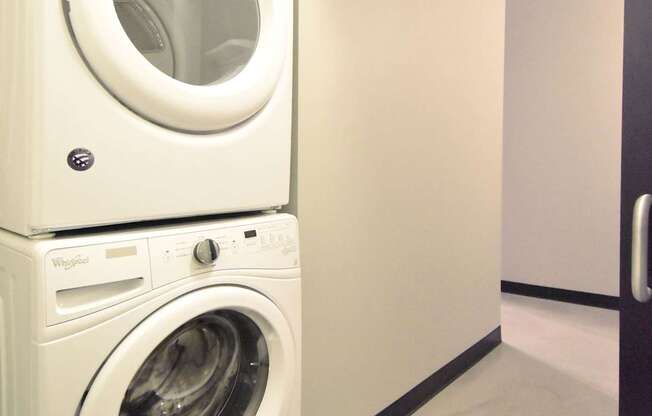 Two white front loading washing machines stacked on top of each other.