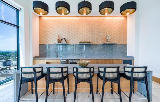 Community bar with tailored seating, layered lighting, and stone surfaces designed for casual gathering, conversation, and hosted events.