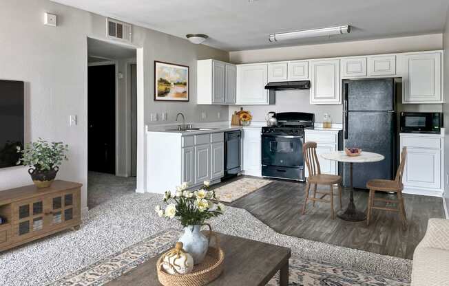 a kitchen and living room with white cabinets and black appliances