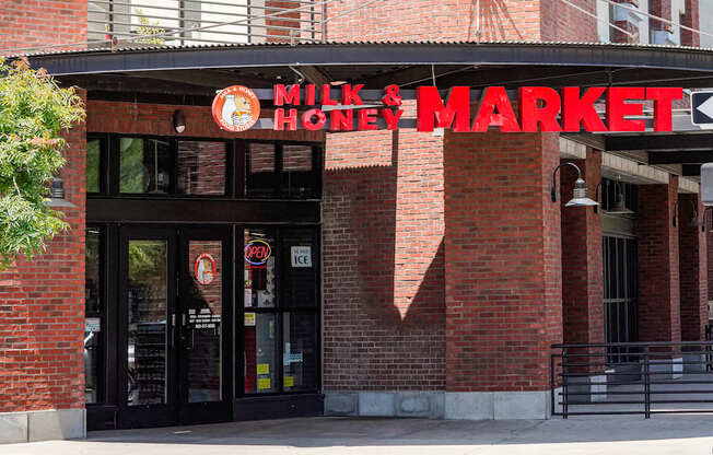 The entrance to a Milk & Honey Market with a red brick wall.