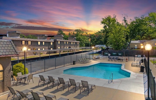 A pool surrounded by chairs and a fence.