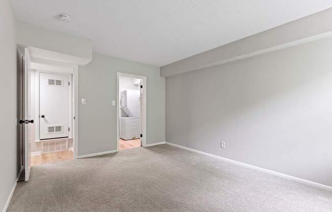 an empty living room with white walls and a door to a bathroom