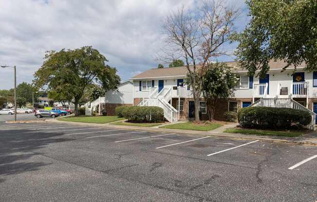 A parking lot in front of a building with a white fence.