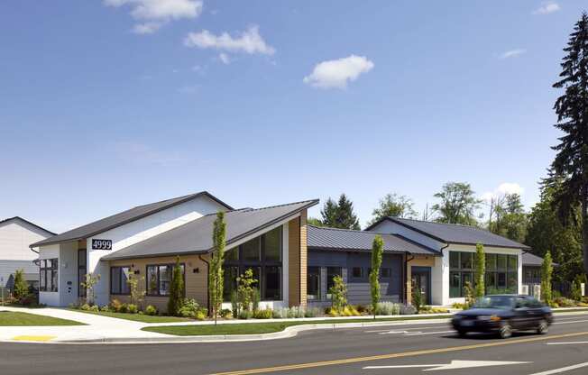 a rendering of the front of the building with a car driving by