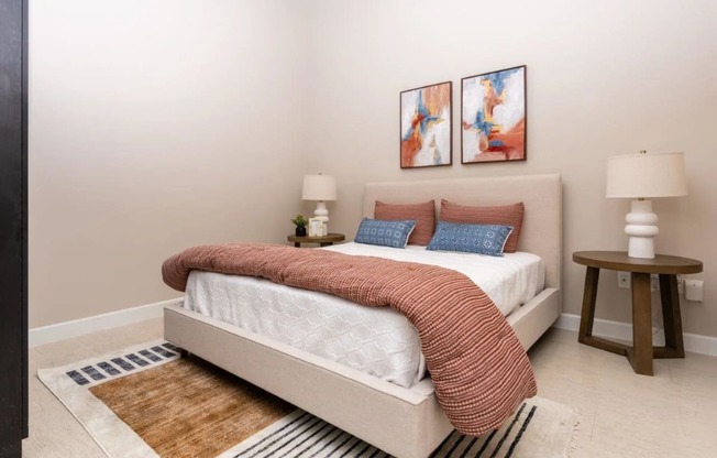 a bedroom with a bed and two paintings on the wall