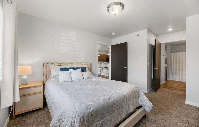 A bedroom with a large bed and a nightstand with a lamp.