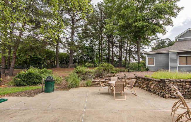 A backyard with a stone wall and a table set for four.