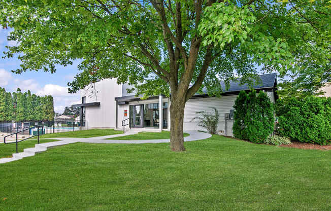 A tree in front of a building with a white fence in the background.