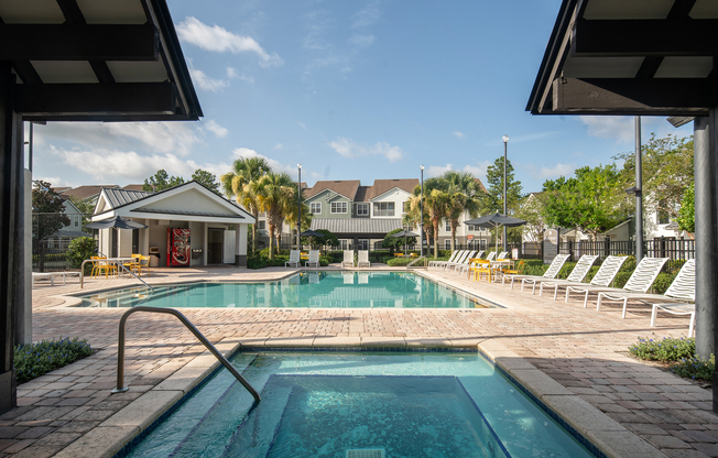 The pool area at our apartments in Tampa, featuring a hot tub, reclining chairs, umbrellas and a clubhouse.