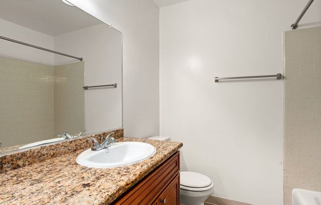 A bathroom with a granite countertop and a white toilet.