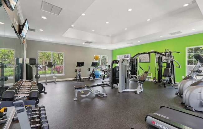A gym with a variety of equipment including treadmills, weights, and exercise machines.