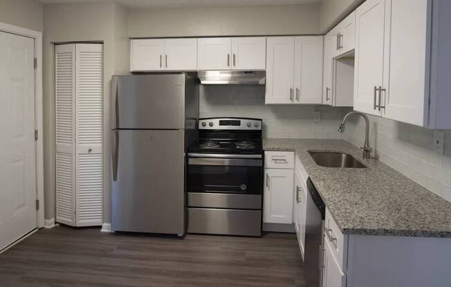 A kitchen with a refrigerator, oven, and sink.