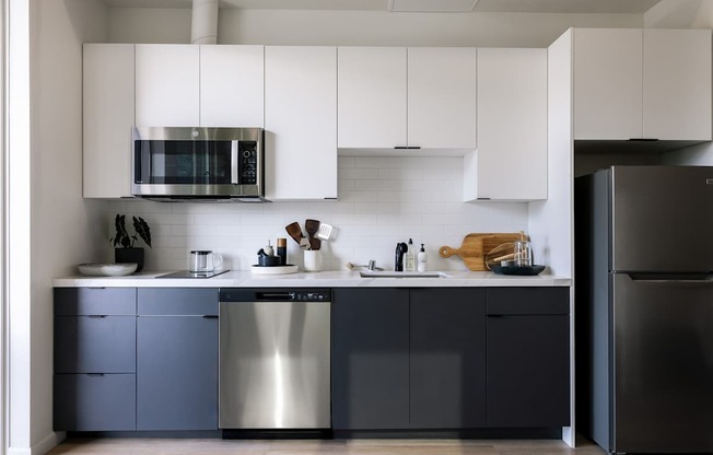 A modern kitchen with a stainless steel dishwasher and a black refrigerator.