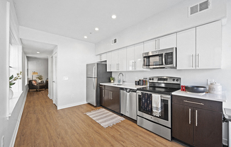 Open kitchen layout with stainless steel appliances and vinyl hardwood floors in student apartment rental
