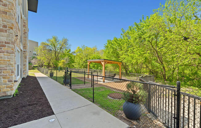 A black fence runs along a sidewalk in a residential area.