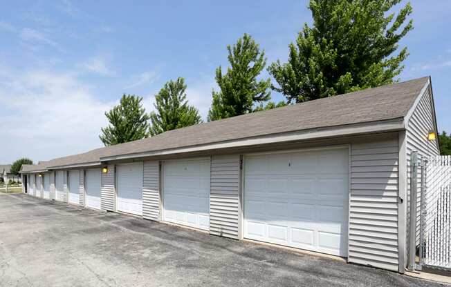 a row of garages with a fence and trees in the background