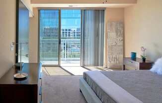 A bedroom with a large bed and a view of a cityscape through the window.