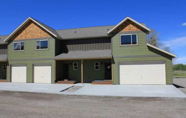 the front of a green house with two garage doors at Copper Pines, Bozeman, MT