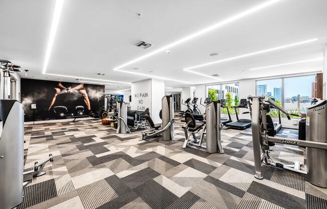 a fully equipped gym with cardio equipment and a large mural of a woman on the wall