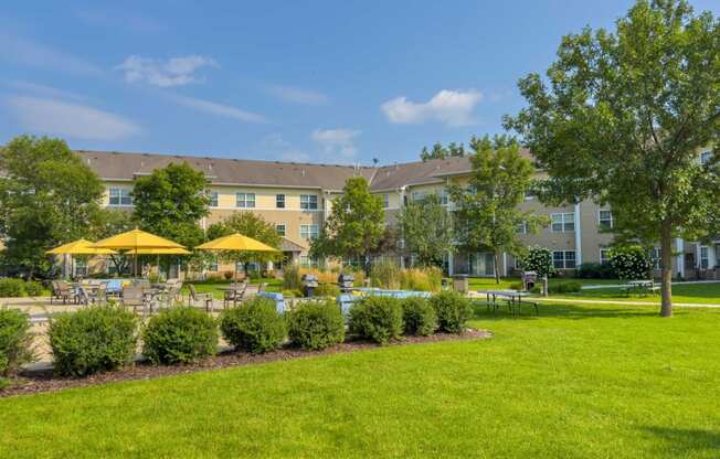 beautiful landscaping with patio with tables chairs and umbrellas