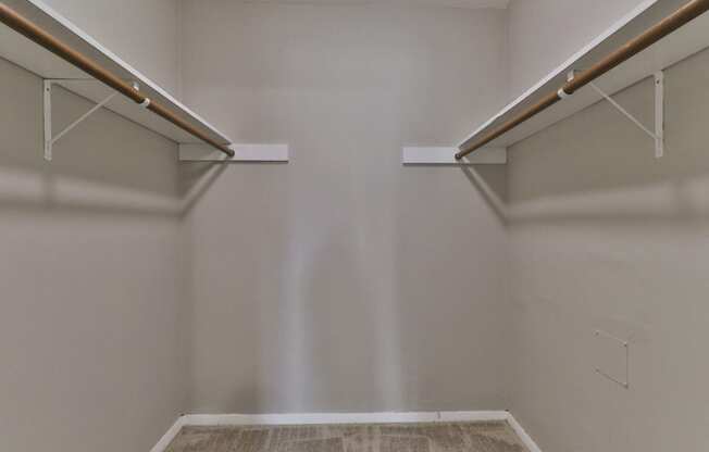 a walk in closet with two shelves and two hanging racks on the wall