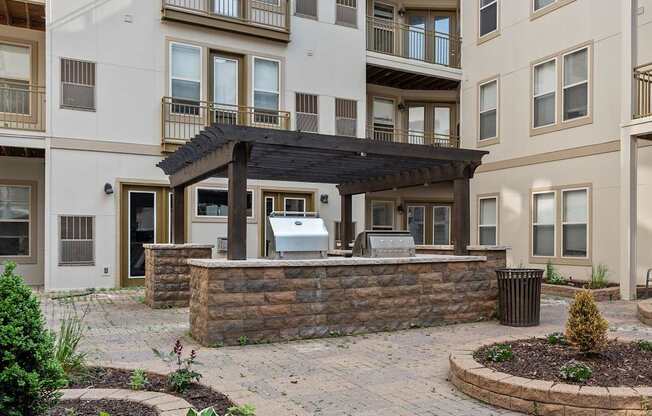 A patio with a table and chairs is surrounded by a stone wall and a garbage can.