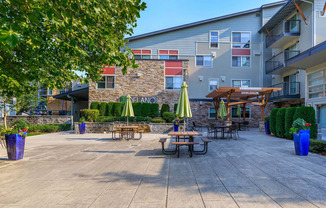 a patio with tables and umbrellas in front of an apartment building at Delano, Washington, 98052
