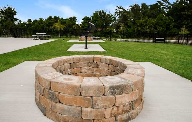 A stone fire pit sits in the middle of a concrete patio.