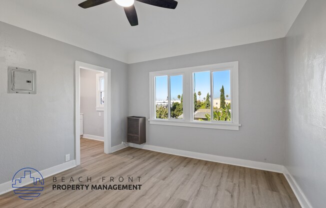 an empty living room with a window and a ceiling fan