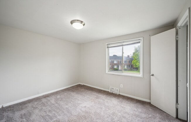 A room with a carpeted floor and a window.