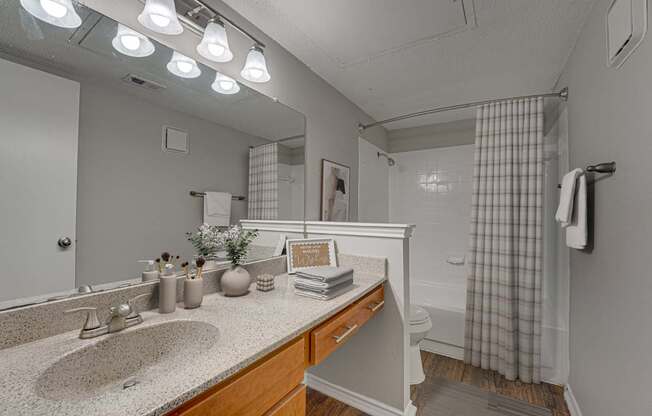 A bathroom with a sink, mirror, and shower.