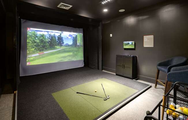 a game room with a golf simulator and a video screen