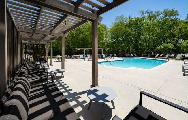 a pool with lounge chairs and a table in the shade