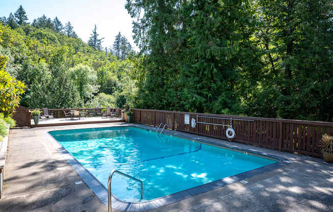 Pool surrounded by a wooden fence and trees.