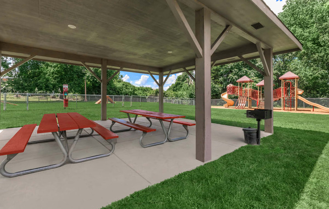 a picnic pavilion with picnic tables in front of a playground