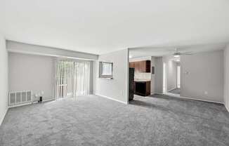 A spacious room with a carpeted floor and a window with blinds.