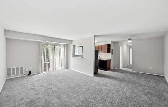 A spacious room with a carpeted floor and a window with blinds.