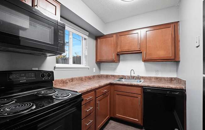 an empty kitchen with black appliances and a granite counter top